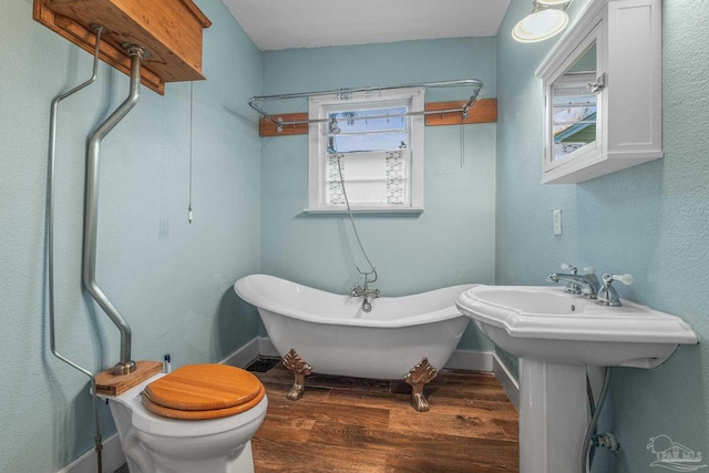 bathroom featuring a washtub, sink, wood-type flooring, and toilet