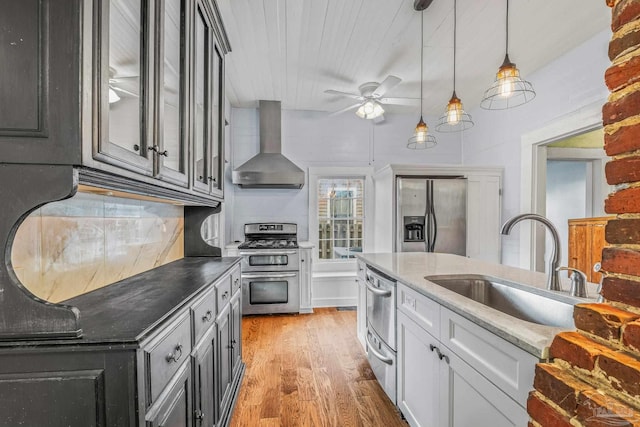 kitchen with sink, light hardwood / wood-style flooring, appliances with stainless steel finishes, backsplash, and wall chimney exhaust hood