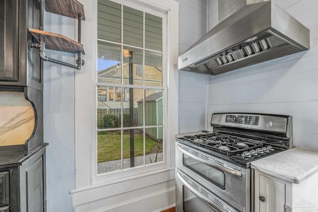 kitchen with range with two ovens and wall chimney range hood