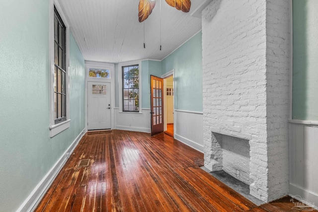 foyer entrance featuring ceiling fan, a fireplace, dark hardwood / wood-style flooring, and crown molding