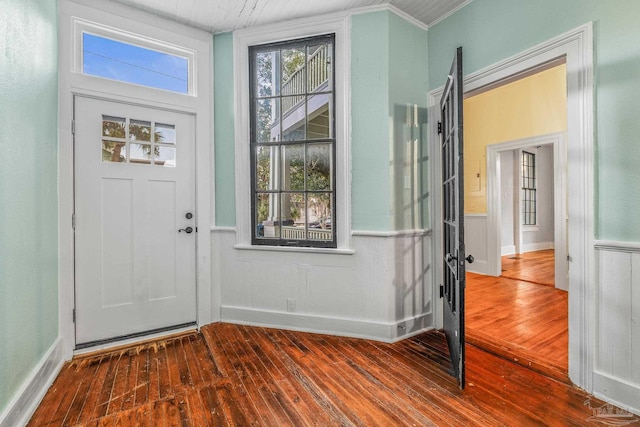 foyer with ornamental molding and dark hardwood / wood-style floors