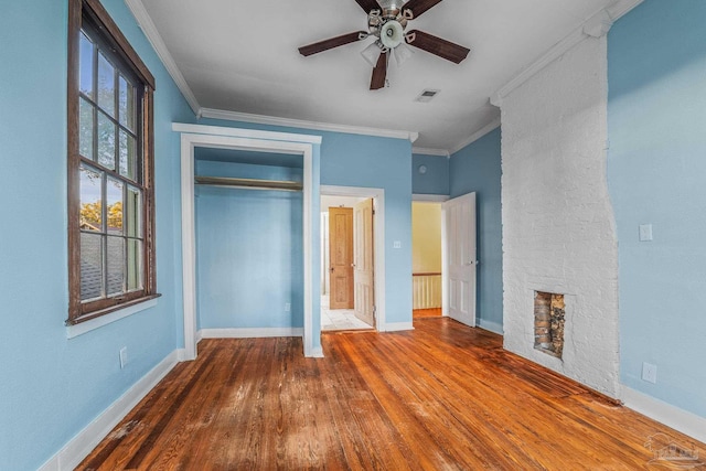 unfurnished bedroom featuring crown molding, a fireplace, ceiling fan, and a closet