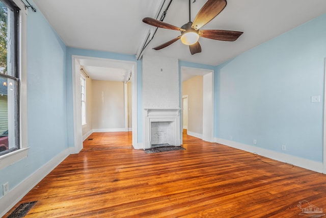 unfurnished living room with ceiling fan, a fireplace, and light wood-type flooring