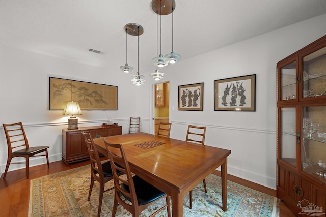 dining room featuring dark wood-style floors, a textured ceiling, visible vents, and baseboards