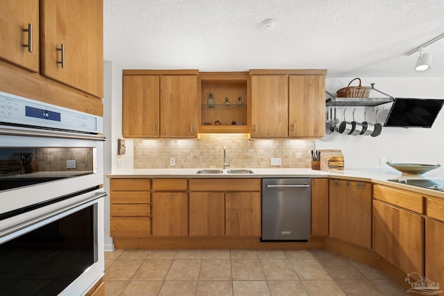 kitchen with white double oven, a sink, light countertops, decorative backsplash, and open shelves