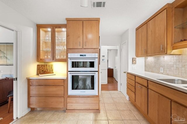 kitchen featuring light countertops, white double oven, glass insert cabinets, and visible vents