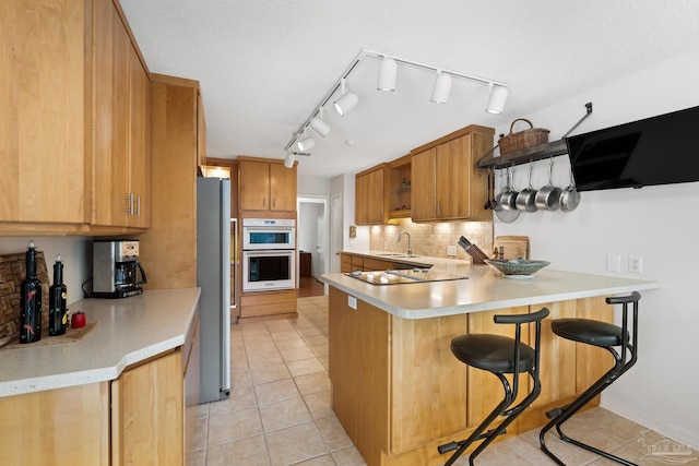 kitchen with a peninsula, a breakfast bar, light countertops, and freestanding refrigerator