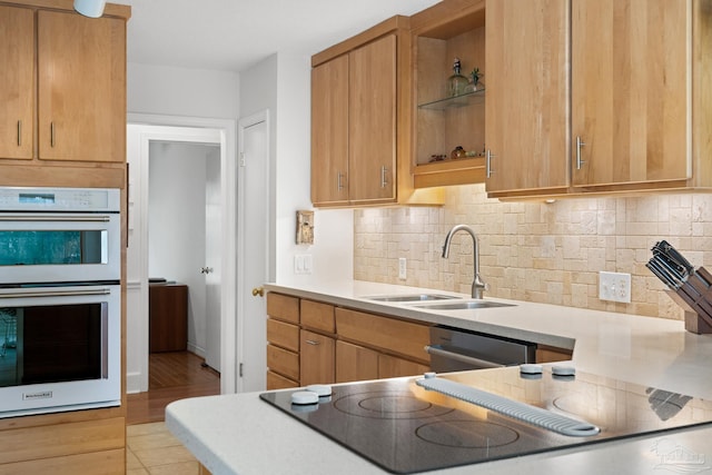 kitchen with double oven, open shelves, a sink, and light countertops