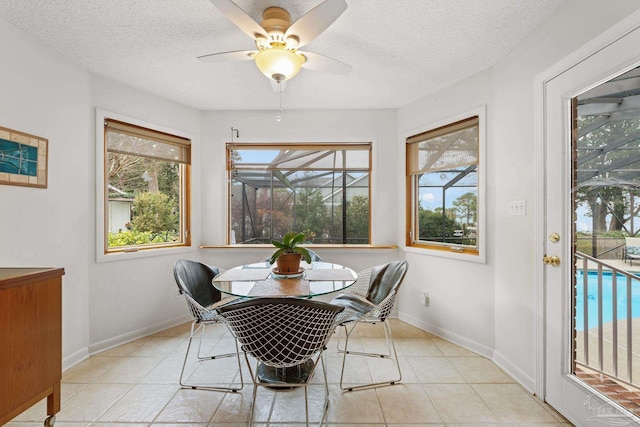 dining area with a textured ceiling, ceiling fan, light tile patterned flooring, and baseboards