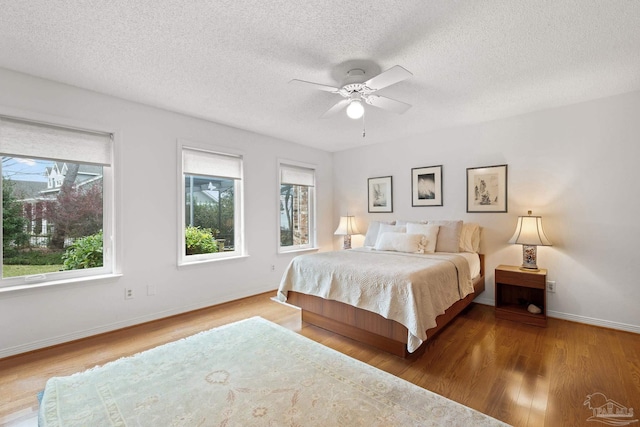 bedroom featuring a textured ceiling, wood finished floors, a ceiling fan, and baseboards