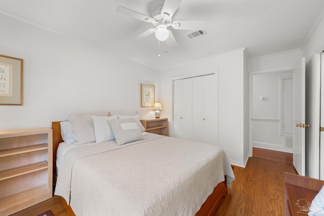 bedroom featuring crown molding, a closet, visible vents, a ceiling fan, and wood finished floors