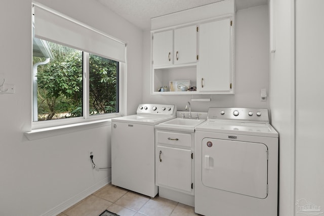 laundry room with light tile patterned floors, a textured ceiling, washing machine and dryer, a sink, and cabinet space