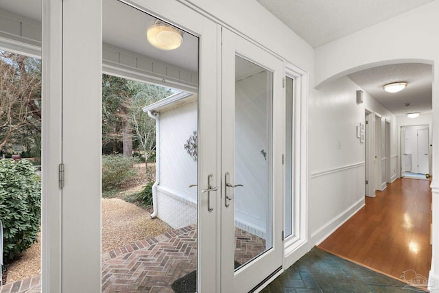 interior space with arched walkways, a textured ceiling, brick floor, and baseboards