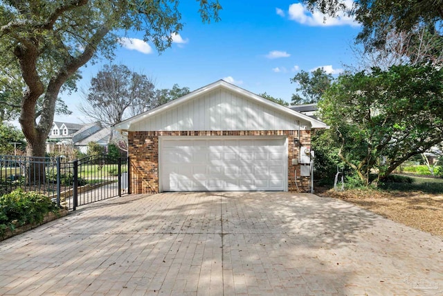 ranch-style home with a garage, a gate, decorative driveway, and brick siding