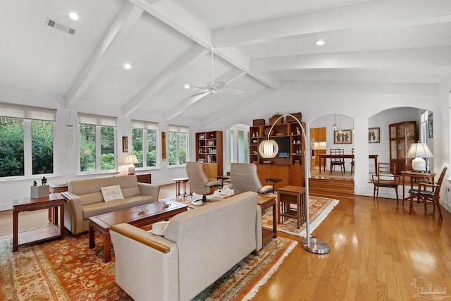 living room featuring arched walkways, ceiling fan, vaulted ceiling with beams, visible vents, and light wood-style floors