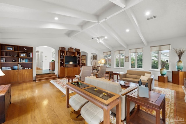 living room with visible vents, arched walkways, ceiling fan, vaulted ceiling with beams, and light wood-style floors