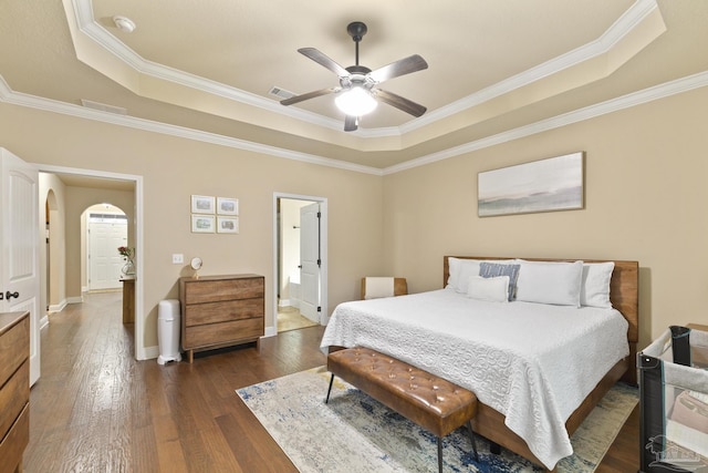 bedroom with arched walkways, dark wood-type flooring, and a raised ceiling