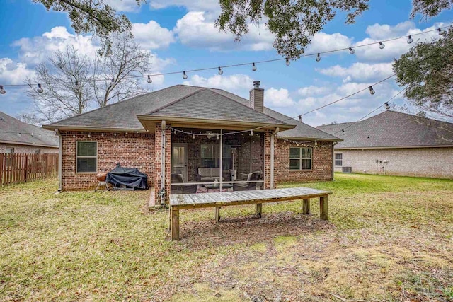 rear view of house with brick siding, fence, a yard, roof with shingles, and a chimney