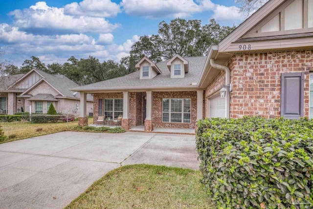 view of front of property featuring covered porch, brick siding, an attached garage, and a front yard