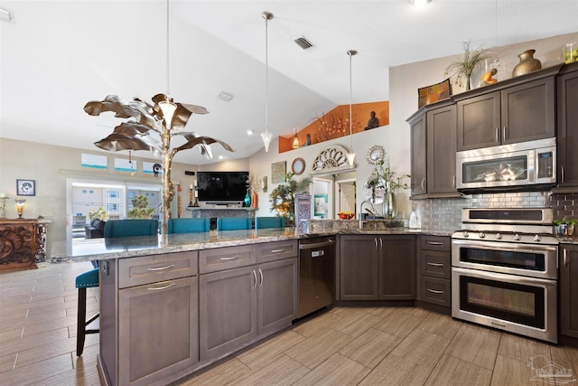 kitchen with open floor plan, vaulted ceiling, stainless steel appliances, decorative backsplash, and a peninsula