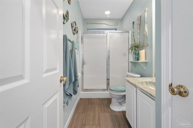 bathroom featuring a stall shower, wood finished floors, toilet, and vanity