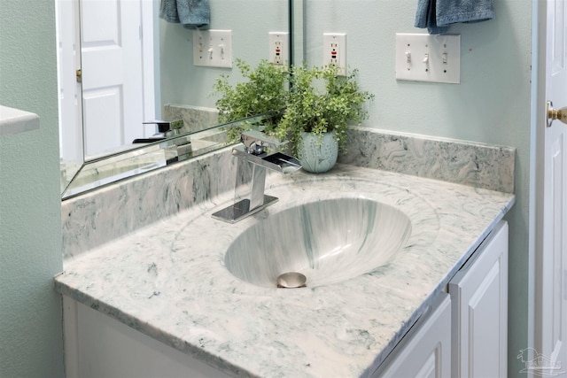 interior space featuring white cabinets, a textured wall, light stone countertops, and a sink