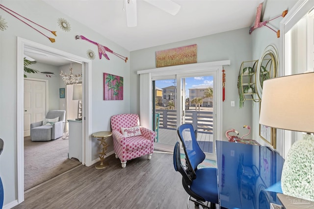 interior space featuring baseboards, wood finished floors, and ceiling fan with notable chandelier