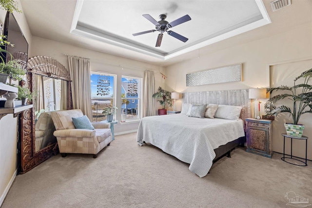 bedroom with carpet flooring, visible vents, baseboards, a ceiling fan, and a tray ceiling