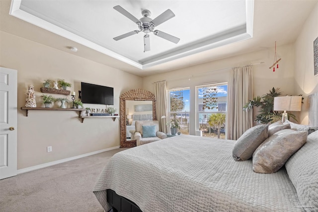 carpeted bedroom featuring baseboards, a tray ceiling, and ceiling fan