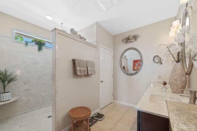 full bath featuring walk in shower, baseboards, double vanity, a sink, and tile patterned flooring