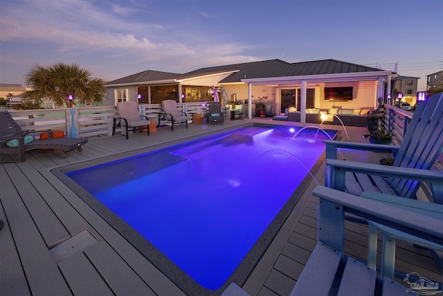 pool at dusk with an outdoor living space, a deck, and an outdoor pool