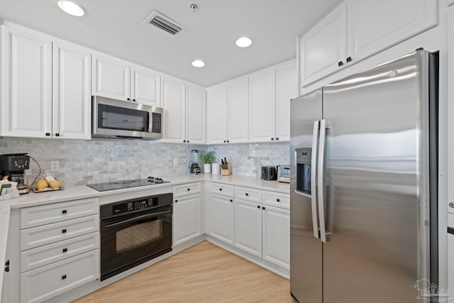 kitchen with black appliances, light hardwood / wood-style flooring, white cabinets, and tasteful backsplash