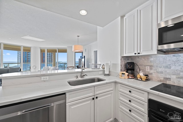 kitchen featuring light stone countertops, black appliances, tasteful backsplash, white cabinetry, and sink