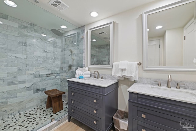 bathroom with a tile shower and vanity