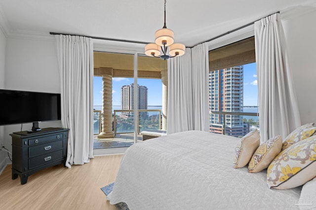 bedroom with access to outside, a notable chandelier, light wood-type flooring, and ornamental molding