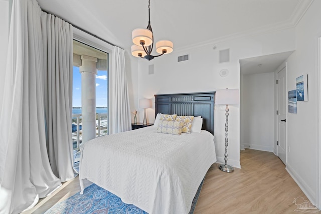 bedroom with hardwood / wood-style floors, an inviting chandelier, and ornamental molding