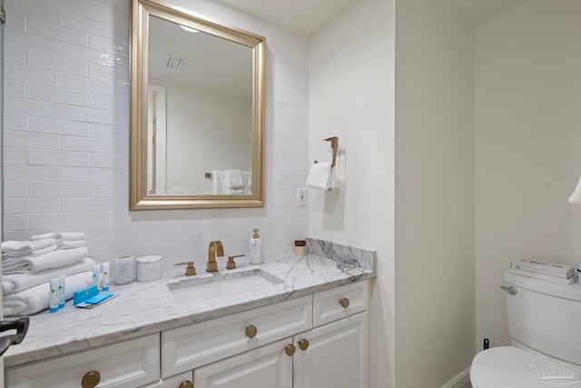 bathroom featuring toilet, decorative backsplash, and vanity