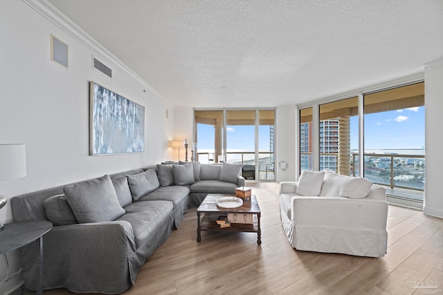 living room featuring a textured ceiling, a water view, crown molding, and expansive windows