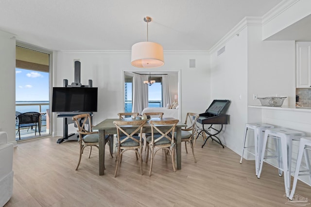 dining space with crown molding and light hardwood / wood-style flooring