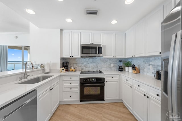 kitchen featuring white cabinetry, black appliances, a water view, sink, and light hardwood / wood-style flooring