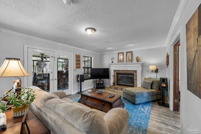 living area with light wood-style floors, a brick fireplace, ornamental molding, and french doors