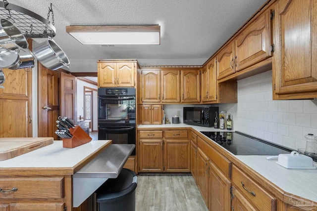 kitchen with brown cabinets, black appliances, and light countertops