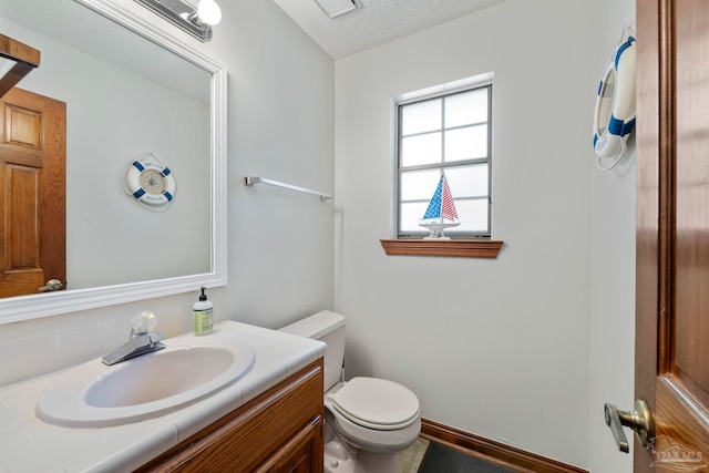 bathroom with toilet, a textured ceiling, and vanity