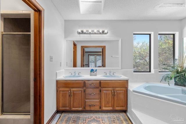 bathroom with a garden tub, a stall shower, and a sink