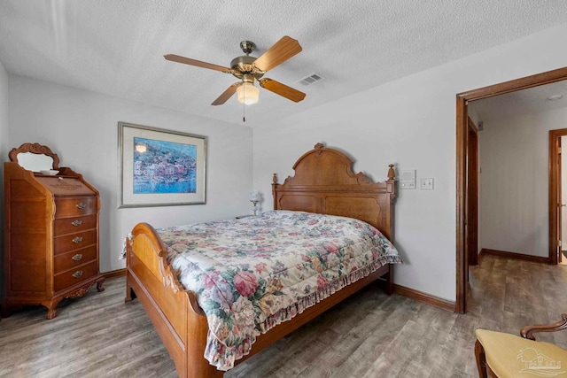 bedroom featuring visible vents, ceiling fan, a textured ceiling, wood finished floors, and baseboards