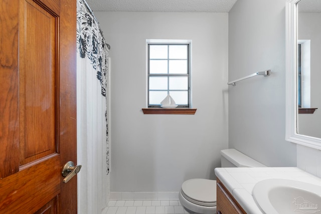 full bath featuring baseboards, toilet, tile patterned floors, a textured ceiling, and vanity