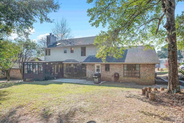 rear view of house with a lawn, a sunroom, a chimney, a patio area, and central AC