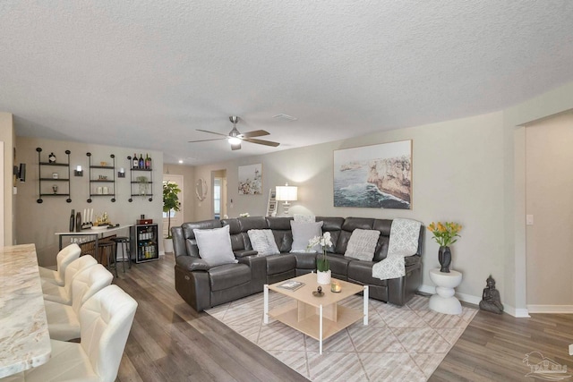 living room featuring a textured ceiling, ceiling fan, and hardwood / wood-style flooring