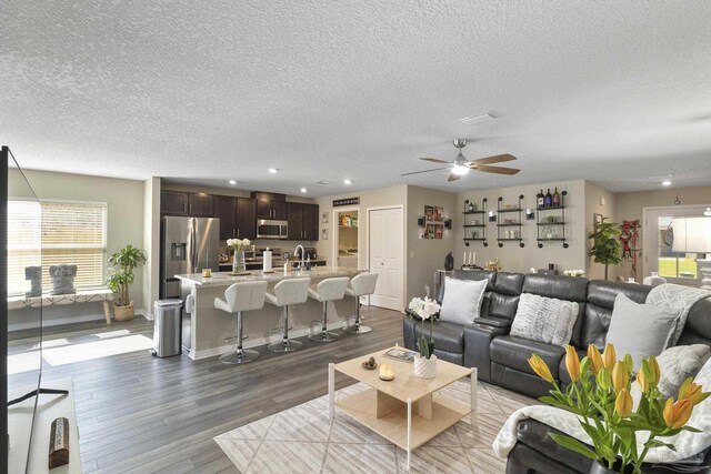 living room featuring a textured ceiling, ceiling fan, and hardwood / wood-style floors