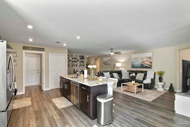 kitchen featuring ceiling fan, appliances with stainless steel finishes, hardwood / wood-style flooring, and an island with sink